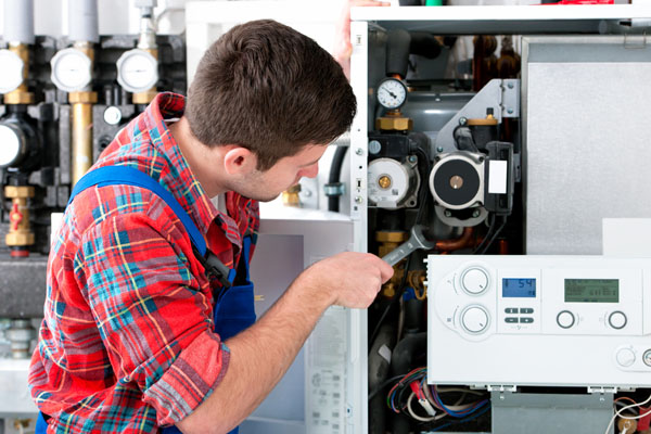 Heating technician repairing boiler controls in Carmichael