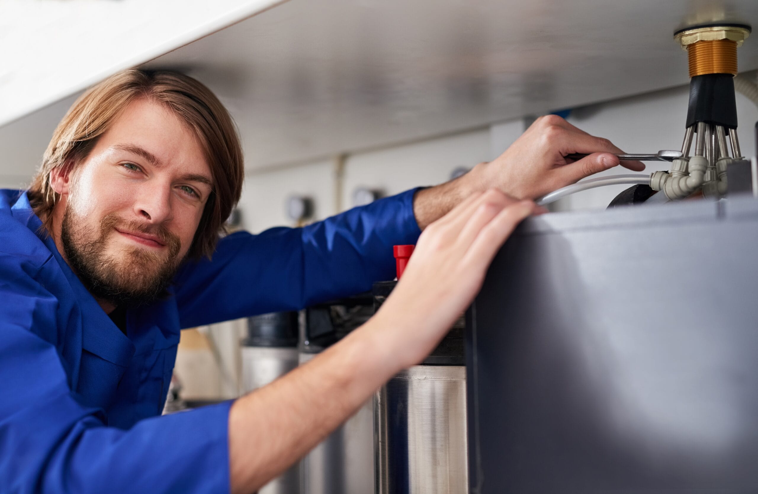 Technician servicing a residential water heater tank in Carmichael